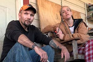 middle age woman and man sitting in the porch with dog pet
